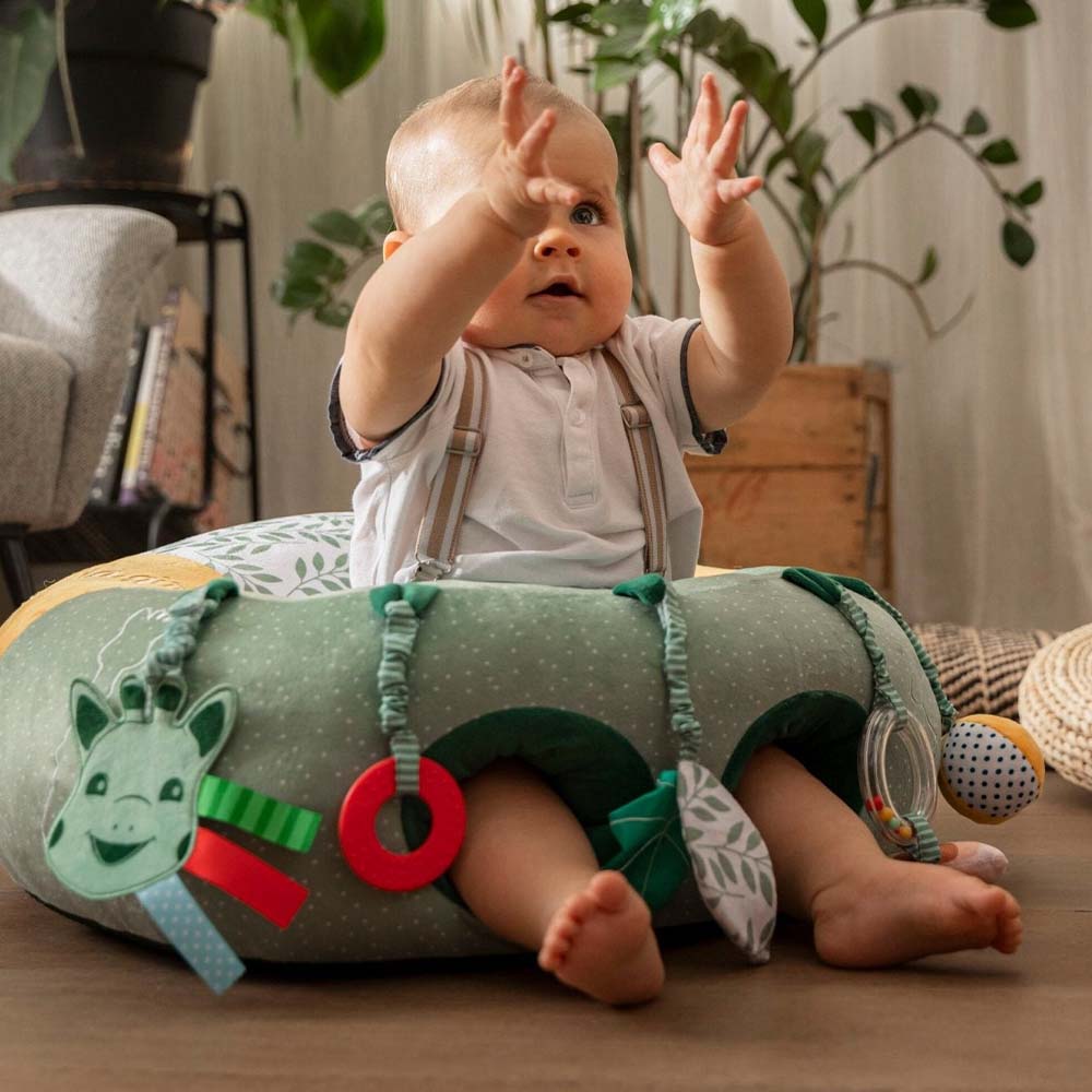 Baby enjoying playtime on a Sophie La Girafe green and white seat