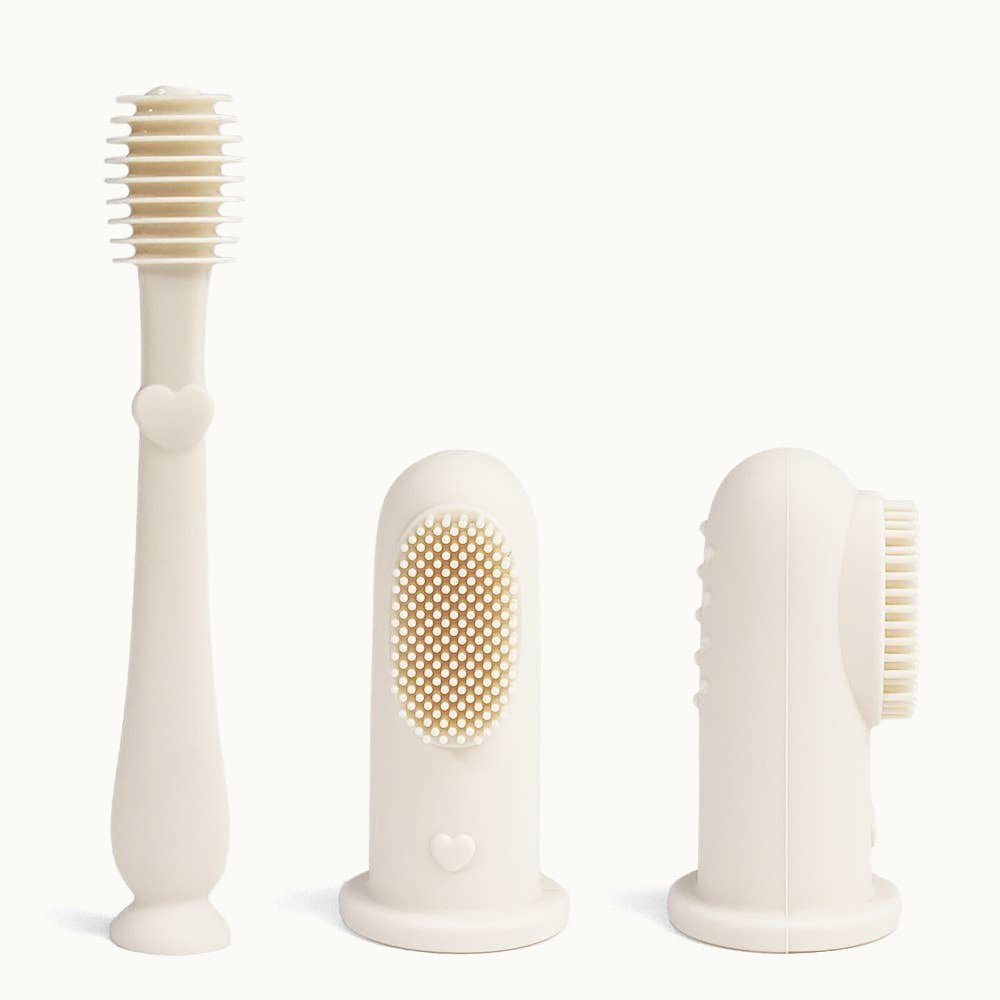 Three Ivory Ali+Oli Baby Finger Toothbrushes on a white surface