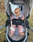 Close-up of a baby in a stroller with the ALI + OLI pacifier holder case nearby