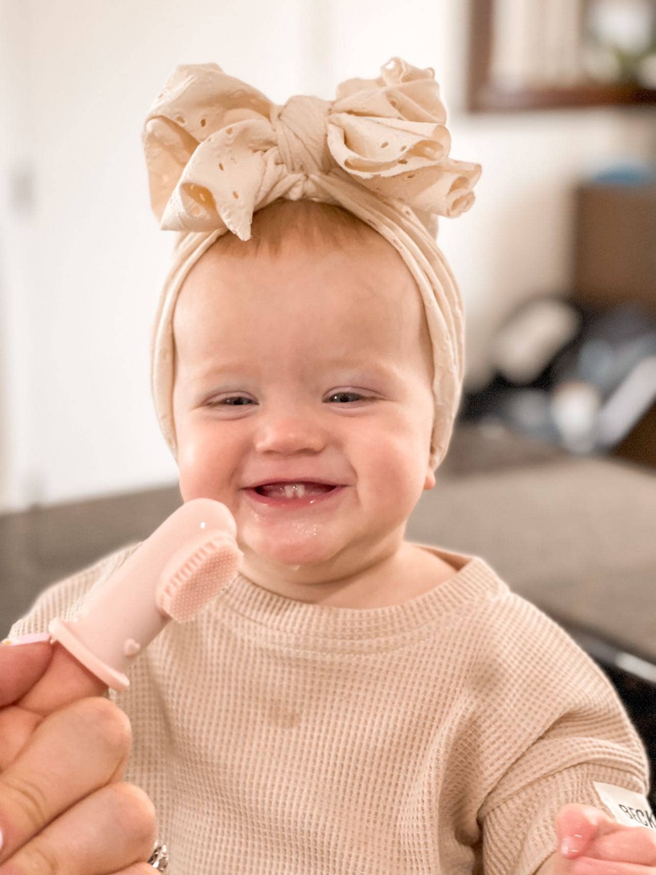 Infant girl happily using her pink finger toothbrush during teething