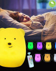 A sleeping child with a Lumipets LED bear night light and remote nearby