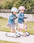 Two kids safely wearing helmets while riding their Scoot & Ride scooters outdoors