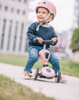 Young girl wearing a safety helmet and riding her rose Highwaykick 1 scooter