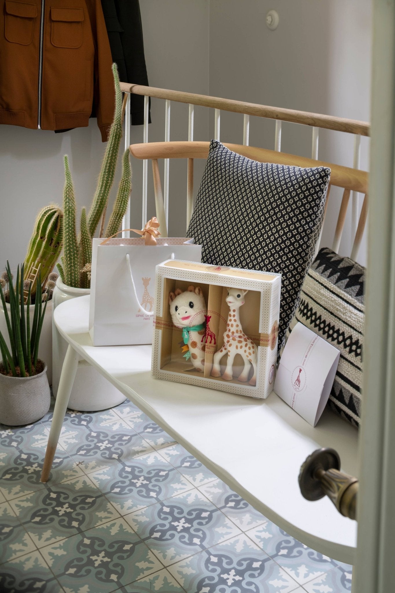 Sophie la Girafe Sophiesticated Set baby gift set with customizable card and gift bag sitting on a bench