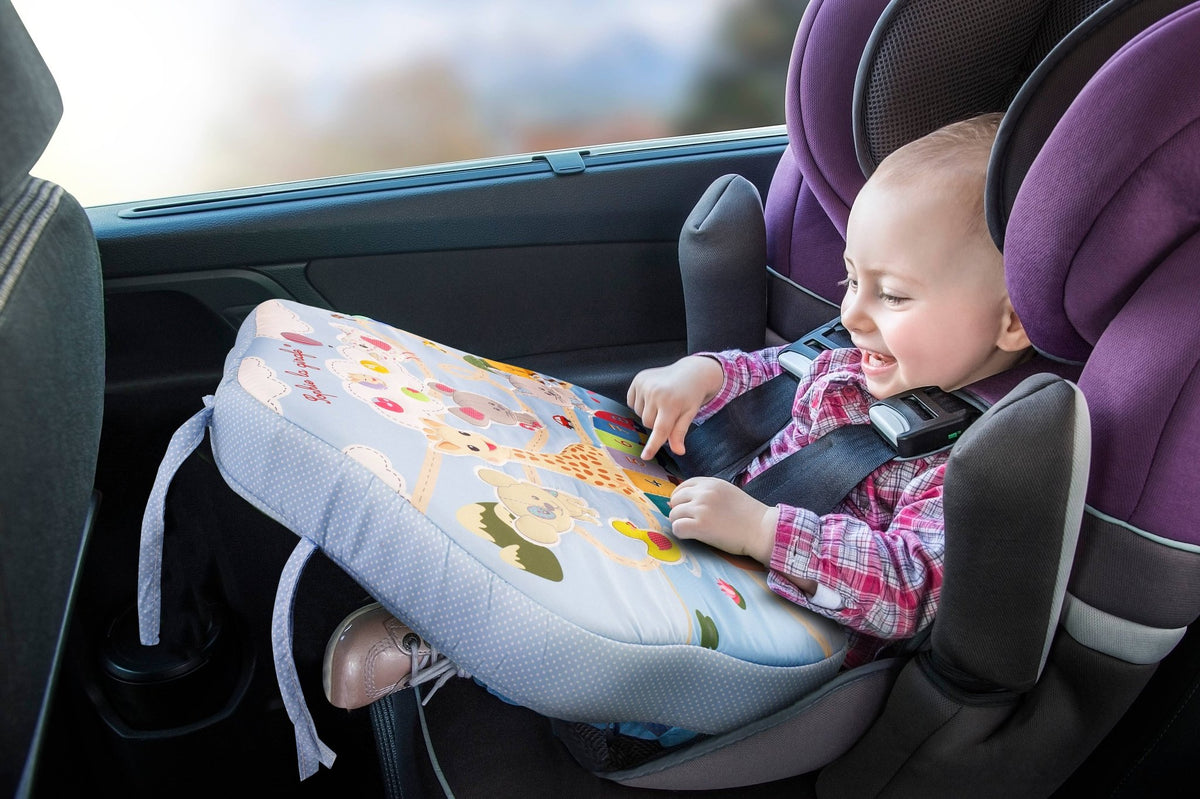 Baby in the car smiling while playing with Sophie la Girafe Touch &amp; Play Board on his lap