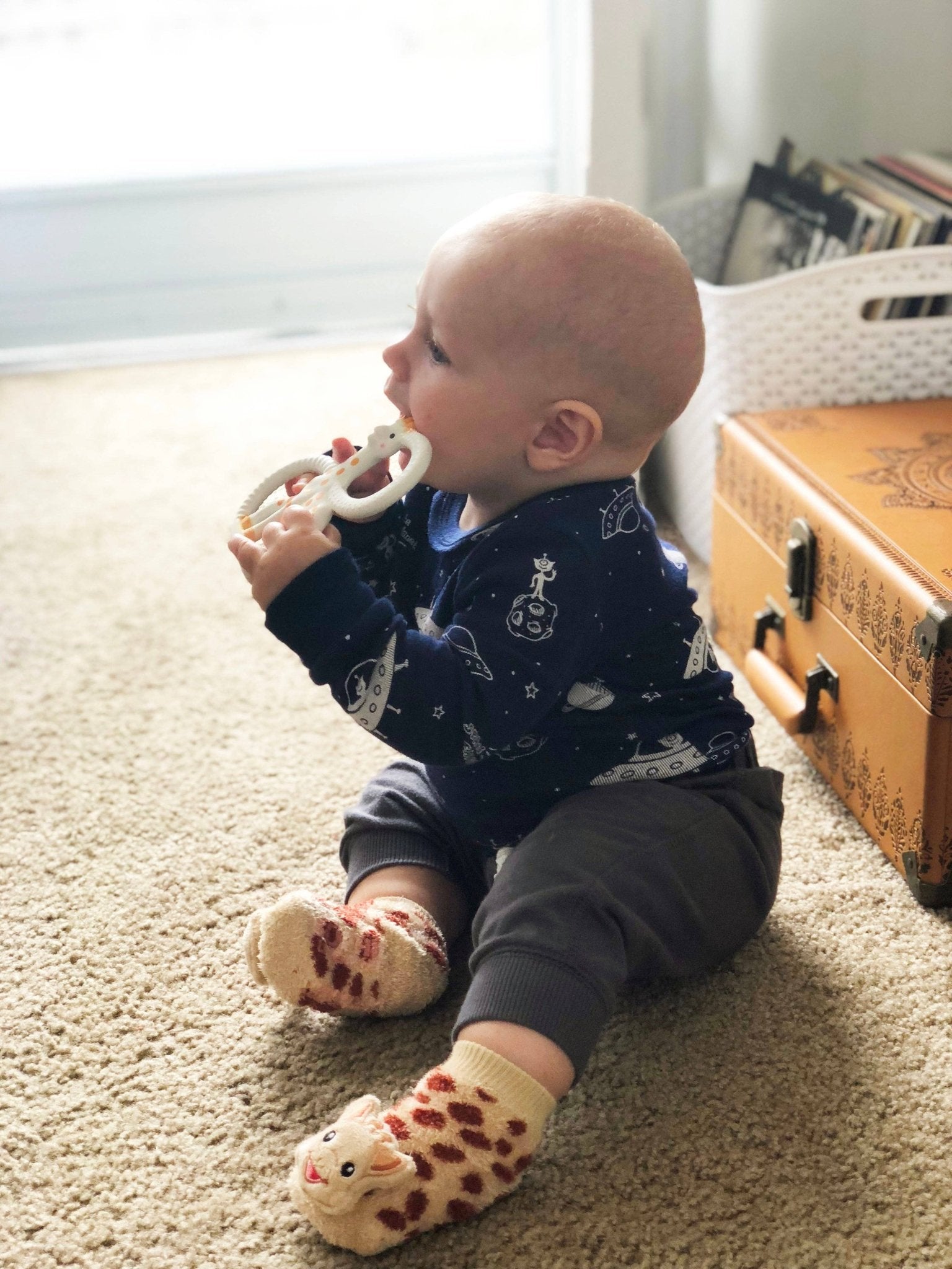 Infant wearing Waddle Rattle Socks playing with a soft giraffe toy