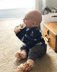 Infant wearing Waddle Rattle Socks playing with a soft giraffe toy