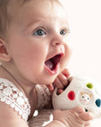 Infant engaging with a Sophie la Girafe So'Pure Senso'ball on a soft surface